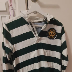 Grön och vit randig tröja - Randig långärmad tröja med knappar högst upp på framsidan och märke. 