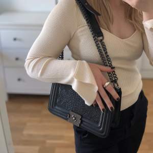 Den perfekta svarta väskan som påminner om Chanel Boy Bag. Boxig väska med kedja som gör det möjligt att bära väskan på axeln eller crossbody. Rymlig med flera fack. Mycket gott skick!     Köpt för 800 kr i London.