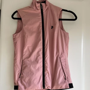 Peak performance väst  - En fin peak performance väst i färgen rosa. Storlek XS. Sparsamt använt dock en liten fläck, se bild.