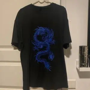 Bekväm oversized svart t-shirt med blå drake print på framsidan, knappt använd 