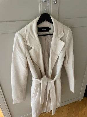 Vero Moda kappa - En ljus kappa från Vero Moda. Storlek XS. Skärp i midjan, avtagbart.   Vill bli av med snabbt, därav billiga priset. 