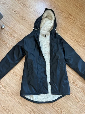 Fodrad regnjacka  - Fodrad regnjacka med luva. Finns ett litet hål i en fickan men går att laga. Sparsamt använd.