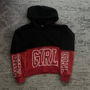 Svart och rött girl hoodie. Det är en tjock hoodie med text på magen och båda ärmarna 