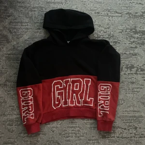 Svart och röd hoodie  - Svart och rött girl hoodie. Det är en tjock hoodie med text på magen och båda ärmarna 