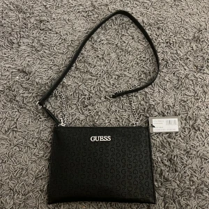 guess väska  - Helt ny guessväska köpt för 750kr med prislappenkvar. Har även dustbag och allt kvar helt oanvänd inuti. Guessmärket består även av av diamanter. 