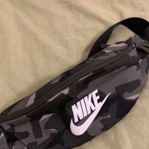Nike camo waistbag - En fin waistbag från Nike som inte längre används. Dragkedjorna fungerar utmärkt. Skriv om fler bilder önskas!