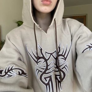 Tribal Hoodie - Feeet beige hoodie med tribals och detaljer i brun och vit.   Thriftad i USA, från märket Sapphire lounge.   Märkt som en storlek XXL, sitter ultra baggy på mig (171cm - Small/36).  Fint vintage skick, någon mini fläck här och där men stör ej helheten! 