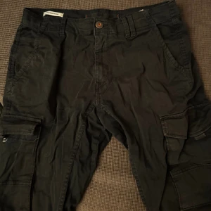 Svarta Cargo byxor herr - Svarta cargo byxor ifrån Jack & Jones. Fina byxor använda fåtal gånger. Strl 32/34