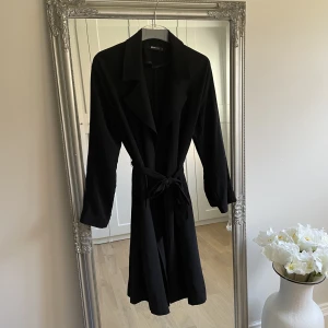 Trenchcoat - Tunn trenchcoat i svart från Bikbok 🖤 sparsamt använd och i fint skick. Perfekt till vår/sommaren när man behöver slänga på sig en jacka. 