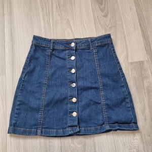 Jeanskjol - Jeanskjol med knappar på hela framsidan. Storlek 36, knappt använd.