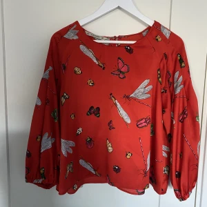 Blus från Zara - Röd fin blus från Zara i silkigt material. Balongärm och en liten knapp i nacken.  Storlek L