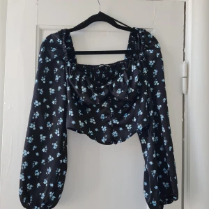 Blommig blus - Blommig blus från ginatricot. Endast provad. V-formad framtill och har knappar, resår bak. 