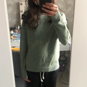 Stickad Tröja - Säljer en jättefin grön stickad tröja från Vero Moda i strl. S. Använd under hösten/vintern 22 och tvättad ett fåtal gånger. Nackdelen är att det blivit ett hål på ena ärmen men hoppas det inte gör allt för mycket. Köparen står för frakten😇