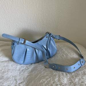 Så fin ljusblå väska med silvriga detaljer, från Ginatricot. Använd en gång. Köparen står för frakten!