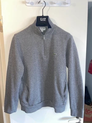 Lacoste tröja sweatshirt 1/2 zip m fickor grå - Skick: 7/10 Storlek: M Ord.pris 2000kr Säljs för att jag tömmer garderoben och behöver inte dessa!
