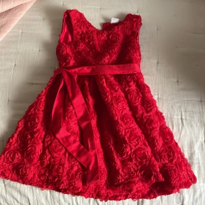 Röd klänning  - Vacker flick klänning i rött, med fint rosmotiv! 🌹helt Oanvänd, nypris 390:- säljes billigt endast 180:-