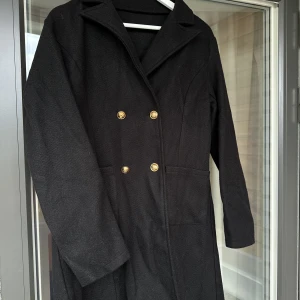 Kappa - Säljer en svart kappa med guldiga knappar.  Kappan är aldrig använd, så som ny.   Färg: Svart Storlek: M/L