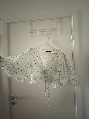 Blus - Söt sommarblus som man knyter själv där fram. Den är lite genomskinlig.