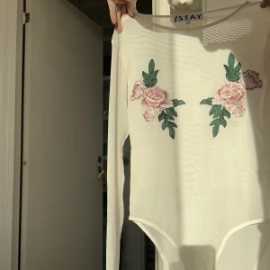 Body med blommiga detaljer - Världens finaste body som knappt kommit till användning! Använd 2 gånger och i nyskick 💕 Köpt på Carlings och är i storlek M men passar definitivt S med. Fråga vad du vill om plagget, en snabb affär uppskattas 🥰