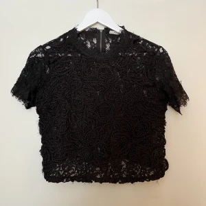 Spets topp - Svart spets topp av en kortare modell. Den är lite högre i halsen och har dragkedja hela vägen baktill. Rak och icke-stretchiga med en lite vidare modell. Endast använd två gånger!