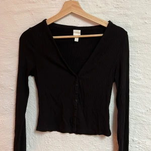 Svart långärmad - Svart långärmad tröja med knappar från hm. Strl S. Endast använd en gång. 