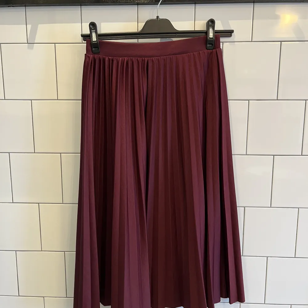 Plisserad vinröd kjol i storlek M från Lager 157 säljes. Kjolen är i mycket bra skick och sparsamt använd. Resår i midjan. Längd: 76 cm Material: 100% polyester. Kjolar.