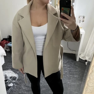 Beige kort kappa  - Säljer denna beiga kortare kappan/jackan från missäy! Avtagbart band i midjan, väldigt fin både öppen och stängd! Köpt här på Plick, använd men fint skick💗storlek s-m Pris kan diskuteras💞  Köparen står för frakt💗