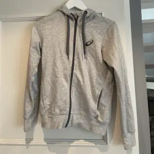 En grå asics zip-hoodie och är i storlek S. Använd fåtal gånger säljer för 150 kr + frakt. Köpte tröjan för 499 kr. 