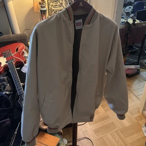 Engelsk Retro Jacka Till kalla sommarkvällar! - Jackan är i mycket fint skick. Vit med orange och gröna ränder. Riktigt trendig nu i sommar. Tidslös design med de rätta färgerna. Storlek XL men jag skulle säga Large. 