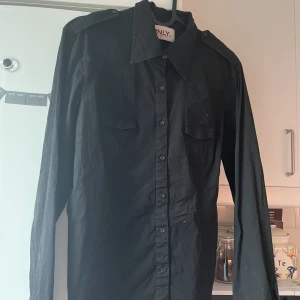 Svart skjorta från ONLY - En svart skjorta från ONLY🤎 Den är väldigt fin och dessutom har den två axeldetaljer (zooma in på bild 1 för att se) ☺️ Det står storlek 42 men skulle säga att det är en 36/38 alltså S/M🤎 