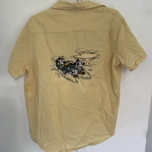 Disney Skjorta - Faaantastisk sommarskjorta!! Härlig färg med ett Nice tryck. Inte min stil längre så därför ges den vidare nu! 