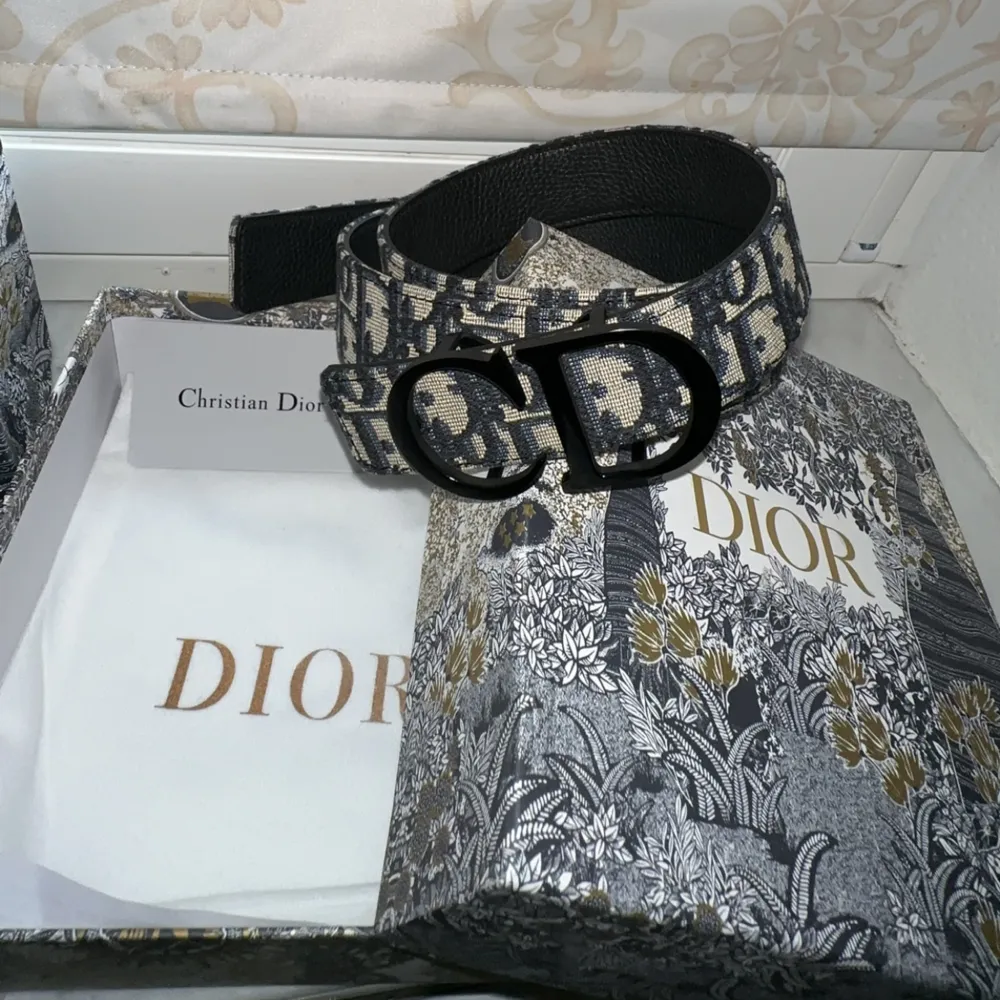 Dior Bälte med svart spänne är en elegant accessoar som levereras i en stilfull Dior-låda och förpackad i en exklusiv Dior-påse. Lådan innehåller en Dior-presentkort som man kan fylla på. Detta bältet är av högsta kvalite och aldrig använts tidigare. . Accessoarer.