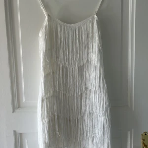 Klänning - Vit klänning med fransar från NA-KD förra året! Den är använd endast en kväll så den är helt som ny! 