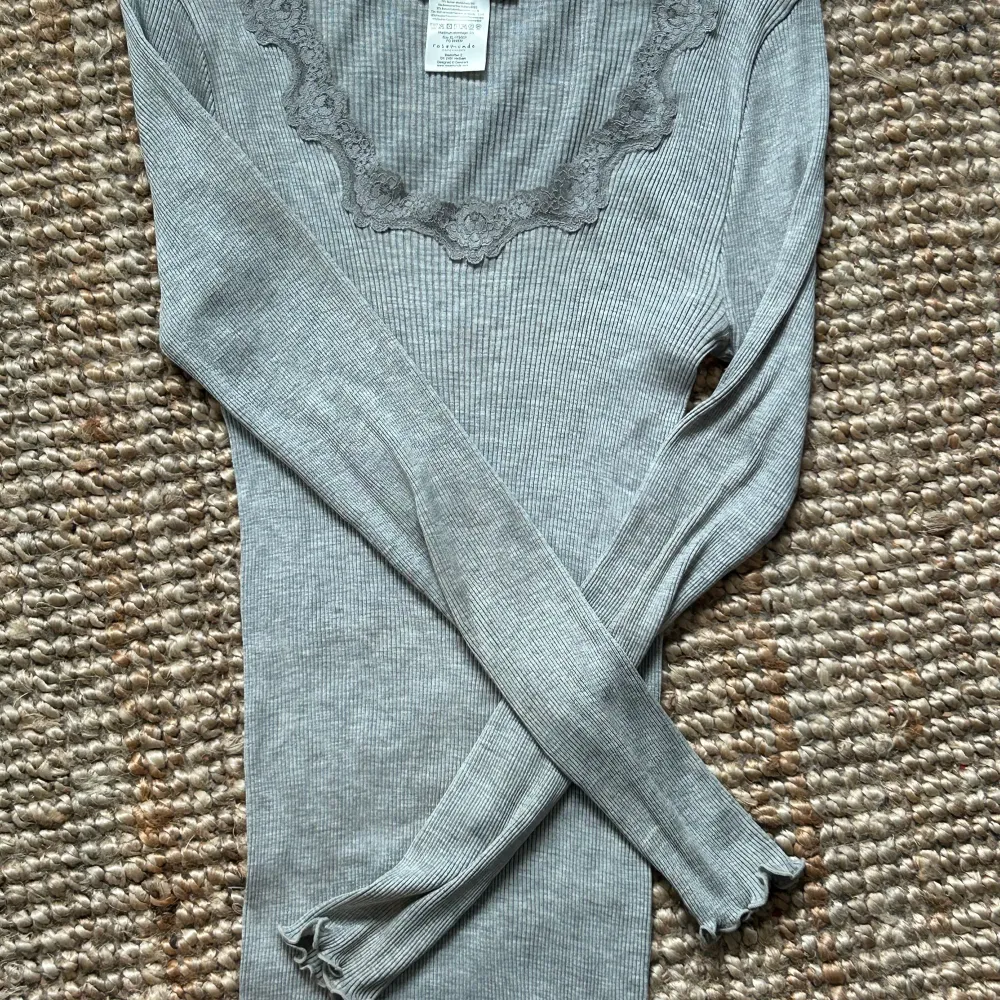 Grå tröja med spets runt om, perfekt till lågmidjade jeans. Den är i XL men väldigt liten i storleken. Från Rosemunde orginal pris 799kr . Toppar.