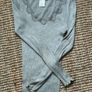 Grå tröja med spets runt om, perfekt till lågmidjade jeans. Den är i XL men väldigt liten i storleken. Från Rosemunde orginal pris 799kr 