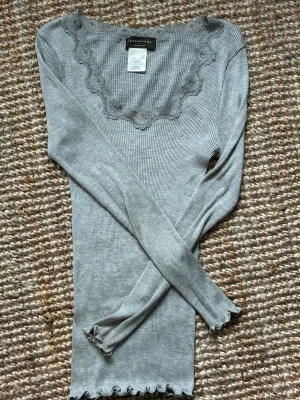 Grå tröja  - Grå tröja med spets runt om, perfekt till lågmidjade jeans. Den är i XL men väldigt liten i storleken. Från Rosemunde orginal pris 799kr 