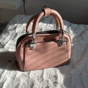 En liten och söt nude rosa väska med silver detaljer. Passar perfekt som vardaglig väska men även till finare tillfällen.