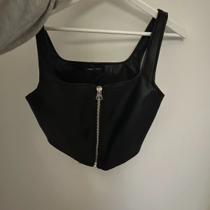 Korsettopp i lädereffekt - Snygg korsettopp i lädereffekt från BERSHKA, aldrig använd bara provad. Det är storlek L men lite k storlken. 