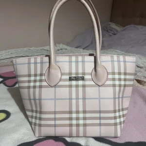 Rosa Burberry väska  - Köpt på secondhand, inte äkta. Medelstor, har några små fack inuti. Den har en missfärgning på bandet (bild 1). Annars supersöt handväska 