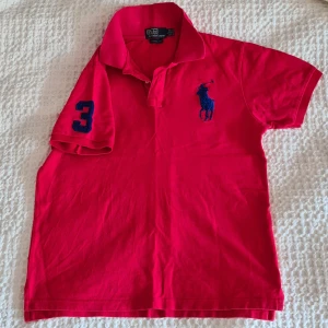 Polo Ralph Lauren stl Large custom fit. - Ralph Lauren pikétröja, polo, röd med big pony i marinblå. Nypris outlet 899:-. Mitt pris 290:- inklusive frakt.  Rökfritt djurfritt o fläckfritt.  Storlek Large. Bra skick, lite använd. Nyskick 