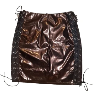 Metallic minikjol med snörning från PRETTYLITTLETHING - Kort kjol i metallic-tyg från Prettylittlething, storlek 36. Dragkedja bak. Superfint skick! Använd gärna köp-knappen 💖💖💖