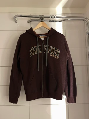 Simon Fraser University Hoodie  - Brun Hoodie. Köp på sellpy. Säljer för den är för liten. Inge slitage eller skador 