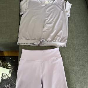 Ett lila träningssätt med t-shirt och shorts. Tröjan har en liten detalj längst ner. Knappt använt, därav bra skick. 