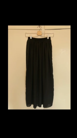 Svart kjol - Svart flowig långkjol i storlek XS/S. Rätt luftig, fin effekt med de dubbla tyglagren