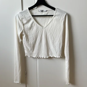 Topp - Vit ribbad topp med V-ringning. Storlek M, aldrig använd.