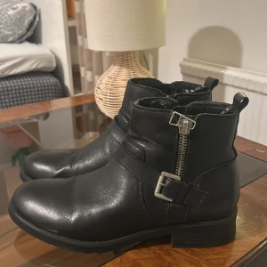 PACE, boots med spänne i stl 41 - Svarta boots i skinn med dragkedja. Tåprofil är rund och klackprofil är bred. Använda bara ett par gånger då storleken inte passar. Bra skick!