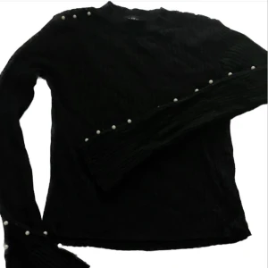 Lång ärmarna svart tröja med pärlor - En långärmad slim fitted tröja med pärlor på båda ärmen. 