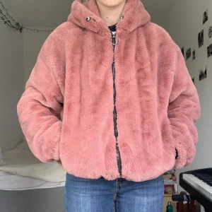 Rosa pälsjacka - Jättemjuk pälsjacka i storlek L från Bershka. Funkar perfekt som oversize till storlek S/M. Stor luva, två fickor, går att spänna åt vid midjan om man vill:)