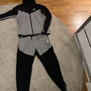 Nike tech Grå svart - Hej, jag säljer denna Nike tech då den växt ut mig och nu står bara i min garderob. Den är i bra skick och inte används så många gånger!