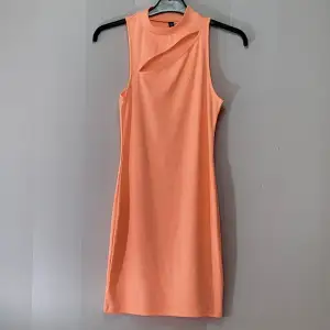 Tajt neon orange/aprikos- klänning. Snitt över brösten. Nyskick